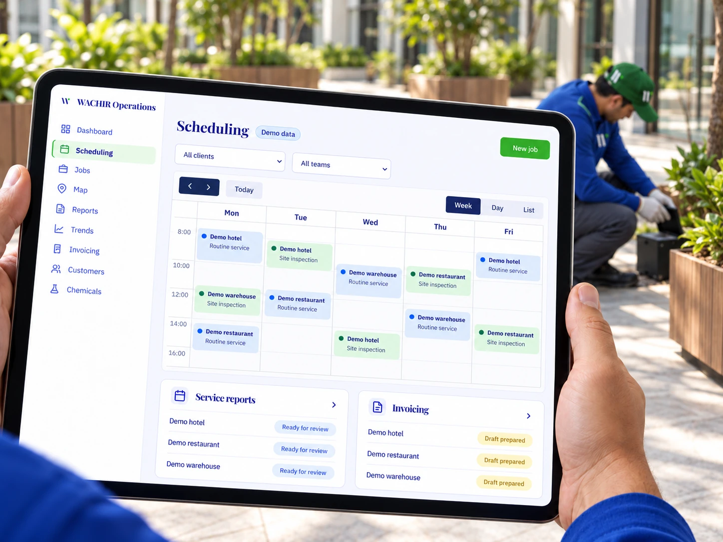 Wachir scheduling platform with fictional demo data on a tablet, with a technician in a blue shirt and green cap in the courtyard